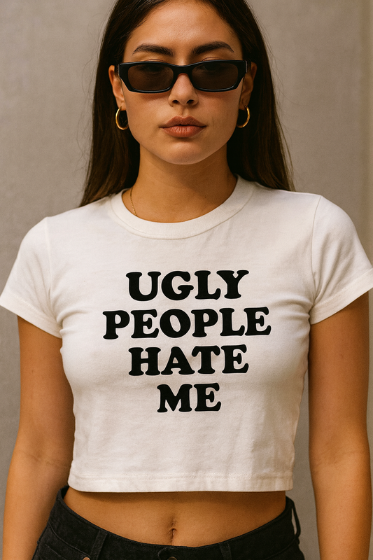 Woman wearing a fitted white crop top with bold black text that says “UGLY PEOPLE HATE ME”